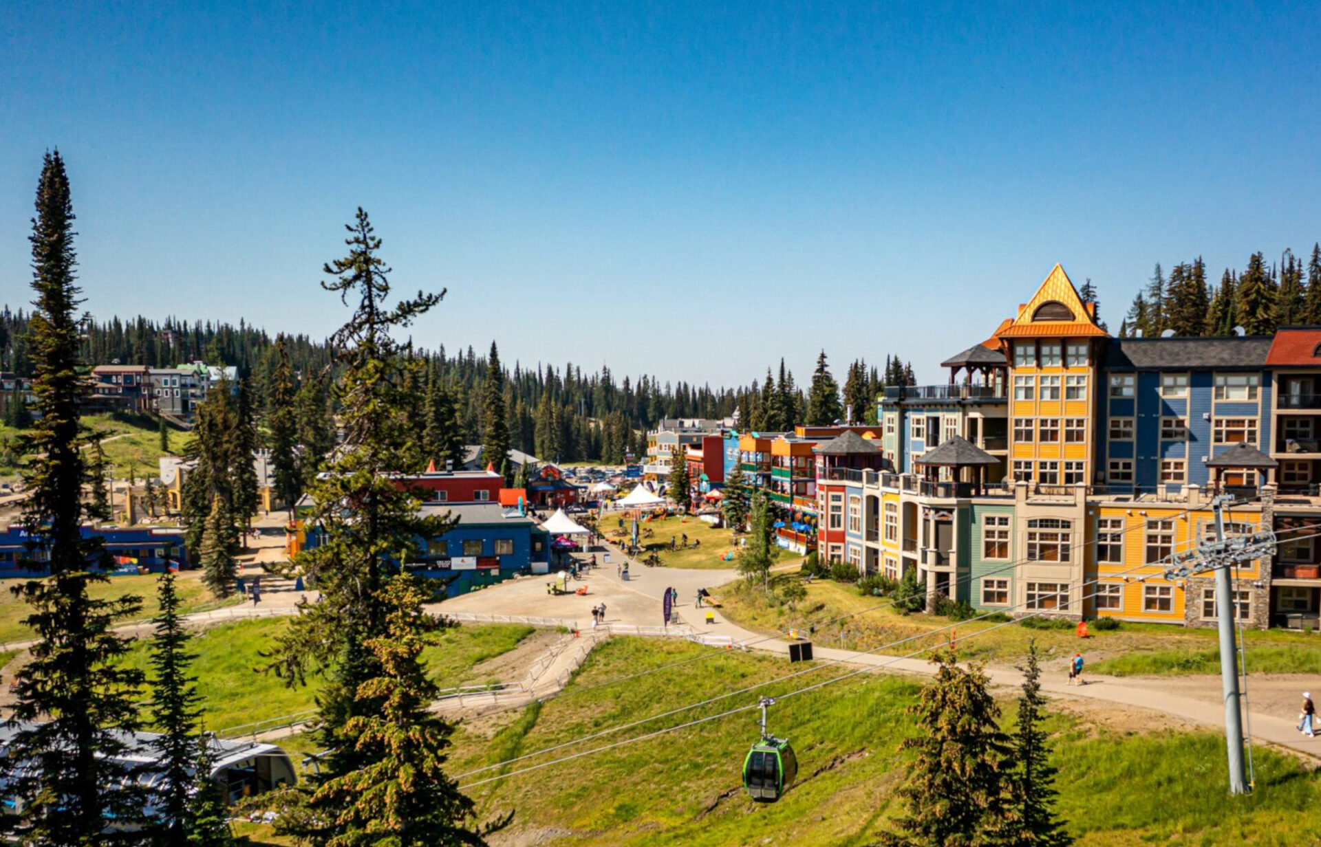 Silver Star village in summer with colourful mountain buildings, forested slopes, and gondola cabins