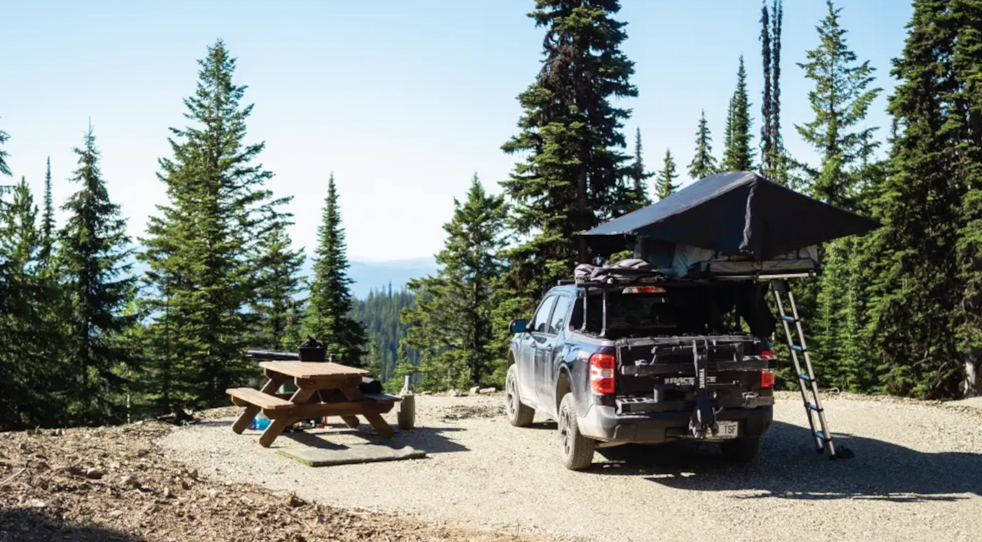 Truck with rooftop tent at an Upper BX Campground site surrounded by evergreen forest